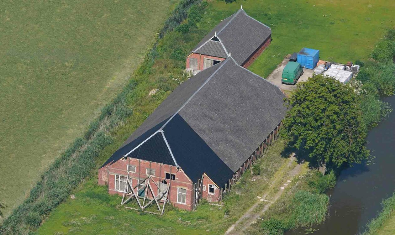 Verzakte boerderij in weiland langs het water