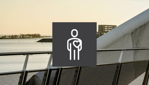 Hoofd Hart en Lef logo Sweco - op een brug met water, wat groen en gebouw op de achtergrond