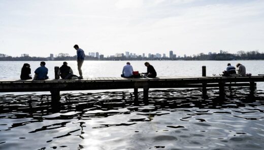 Mensen op steiger bij water, uitkijkend op de skyline van Rotterdam