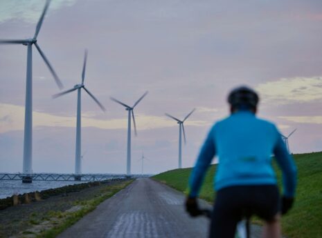 Fietser in de schemering op een Ijsselmeerdijk met windmolens