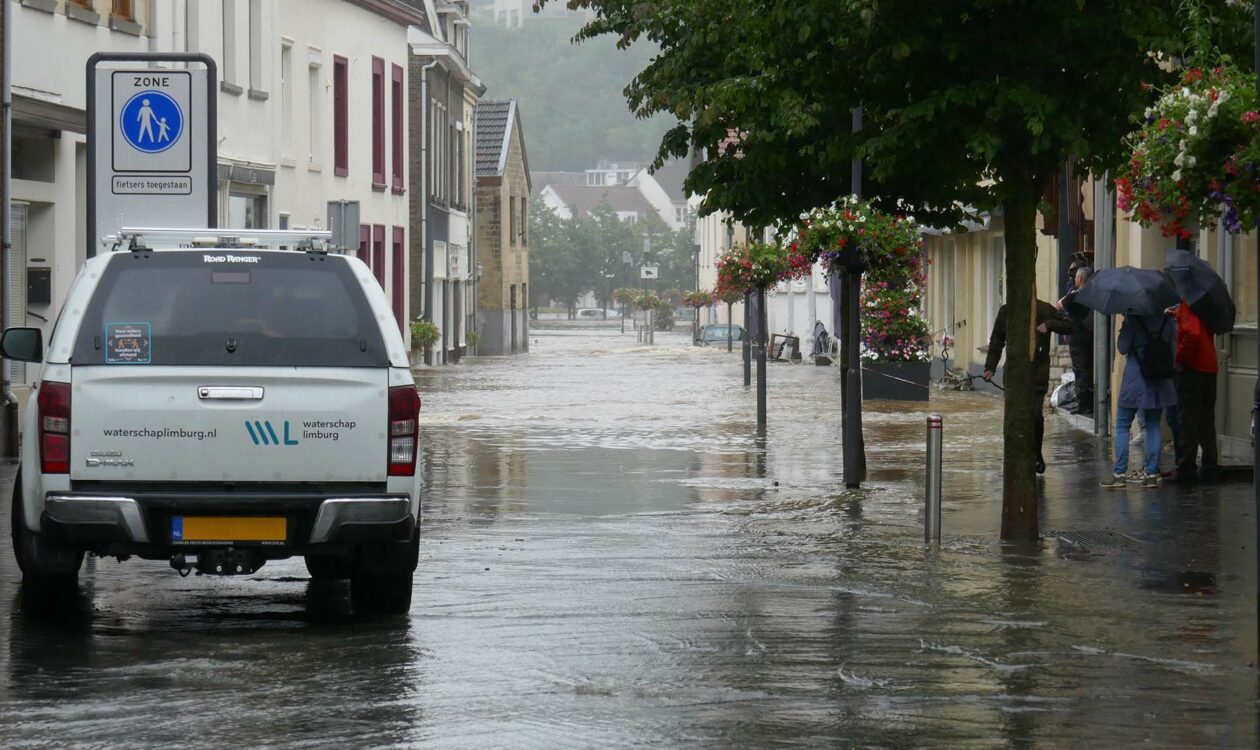 Auto waterschap Limburg rijdt door overstroomde straat