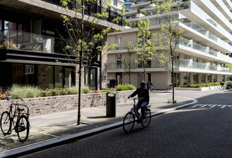 Man fietsend langs hoge flats