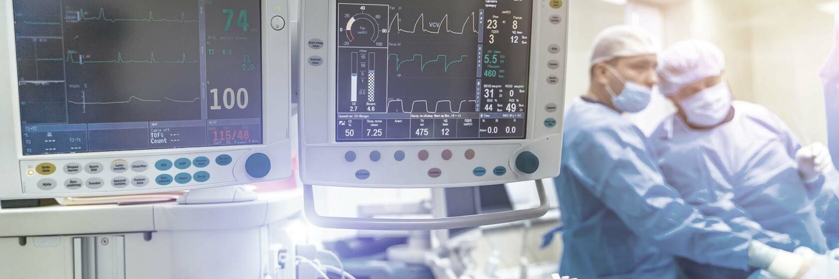 Monitors op de operatiekamer met op de achtergrond doctoren