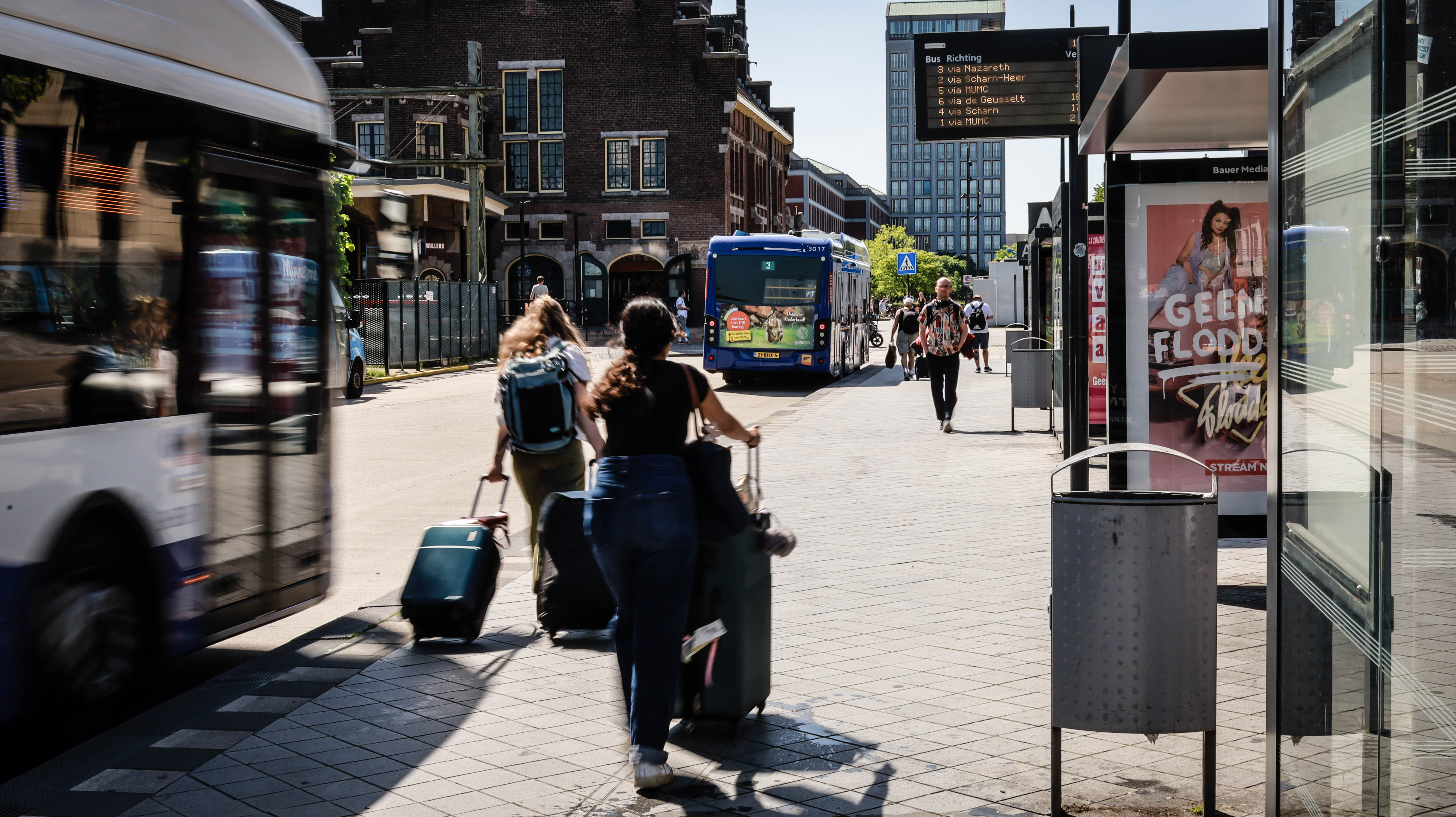 Stationsgebied Maastricht, mensen lopen langs de bus met koffers
