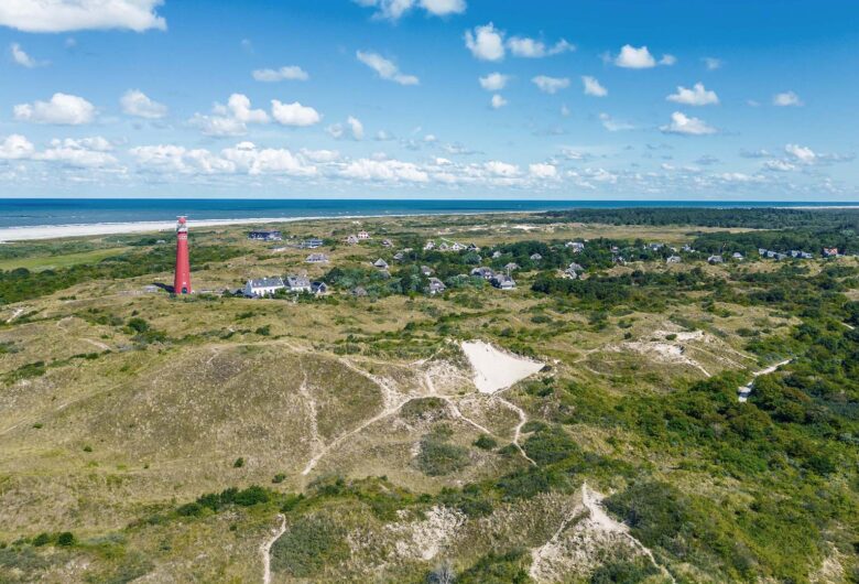 Helikopterview van het eiland met rode vuurtoren en de zee in de verte.