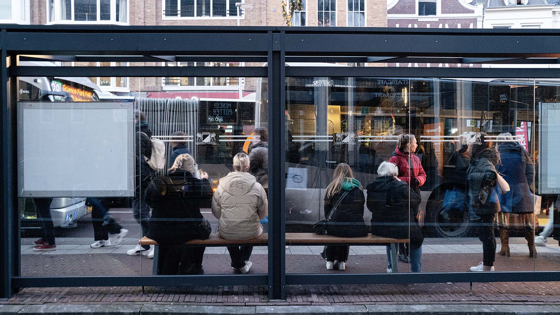 Reizigers wachten op bus bij bushalte