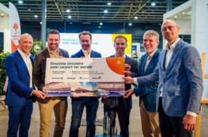 Mensen presenteren bord over grootste circulaire zonnecarport ter wereld op evenement.