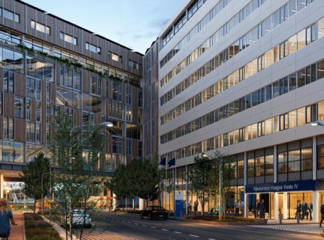 Modern kantoorgebouwen langs straat met fietsers en voetgangers, avond sfeer.
