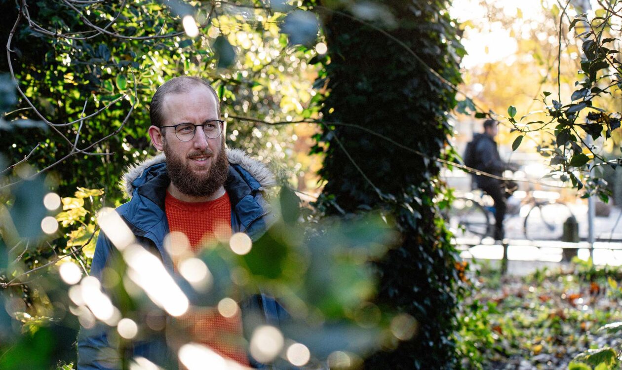Man met baard, Joeri Meliefste tussen groene bomen in stedelijke omgeving.