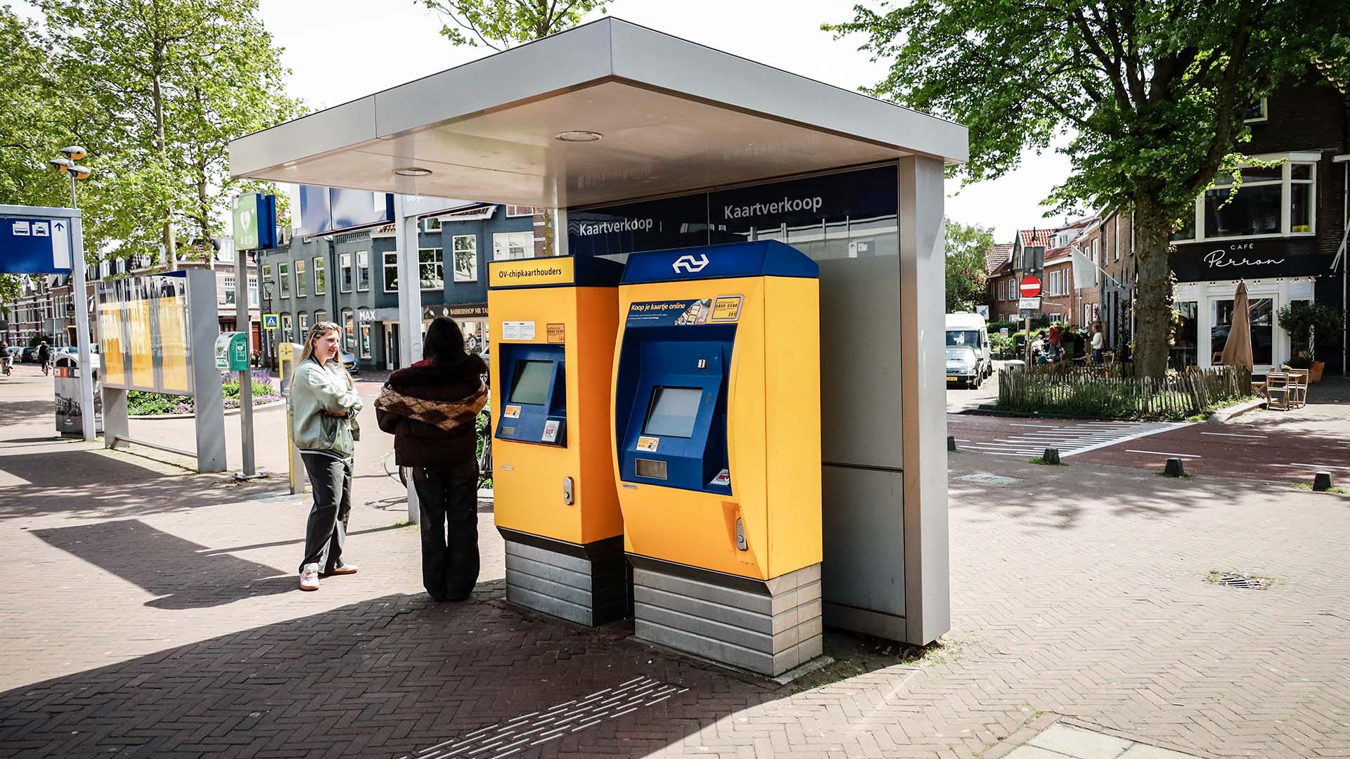 Twee mensen bij kaartautomaten op een busstation