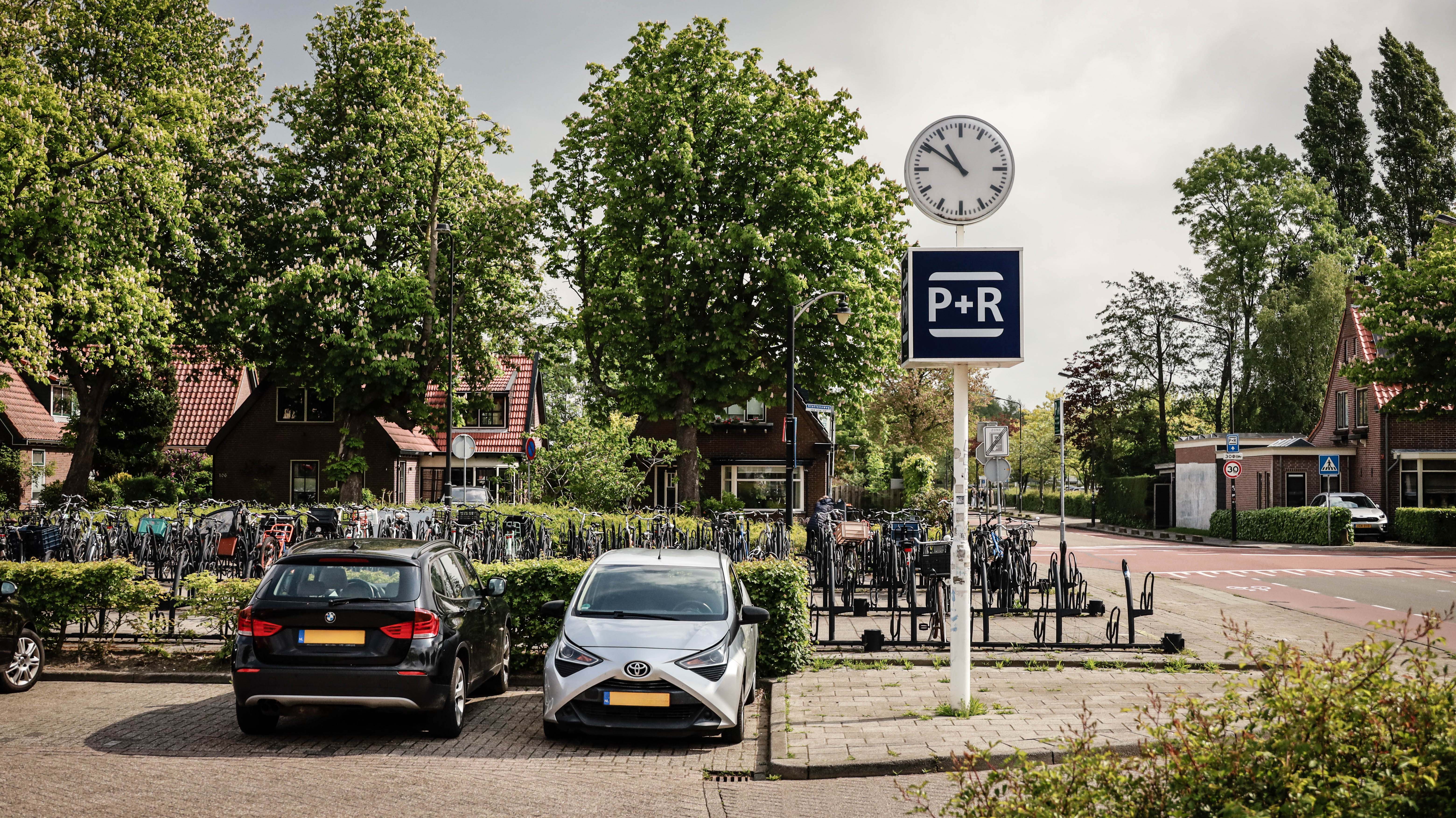 P + R parkeerplaats met twee geparkeerde auto's met groene bomen en struiken op achtergrond