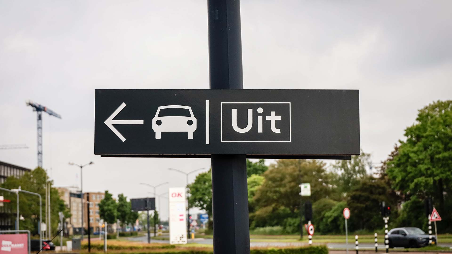 Bord met icoon auto en Uit bij parkeerterrein in stedelijke omgeving