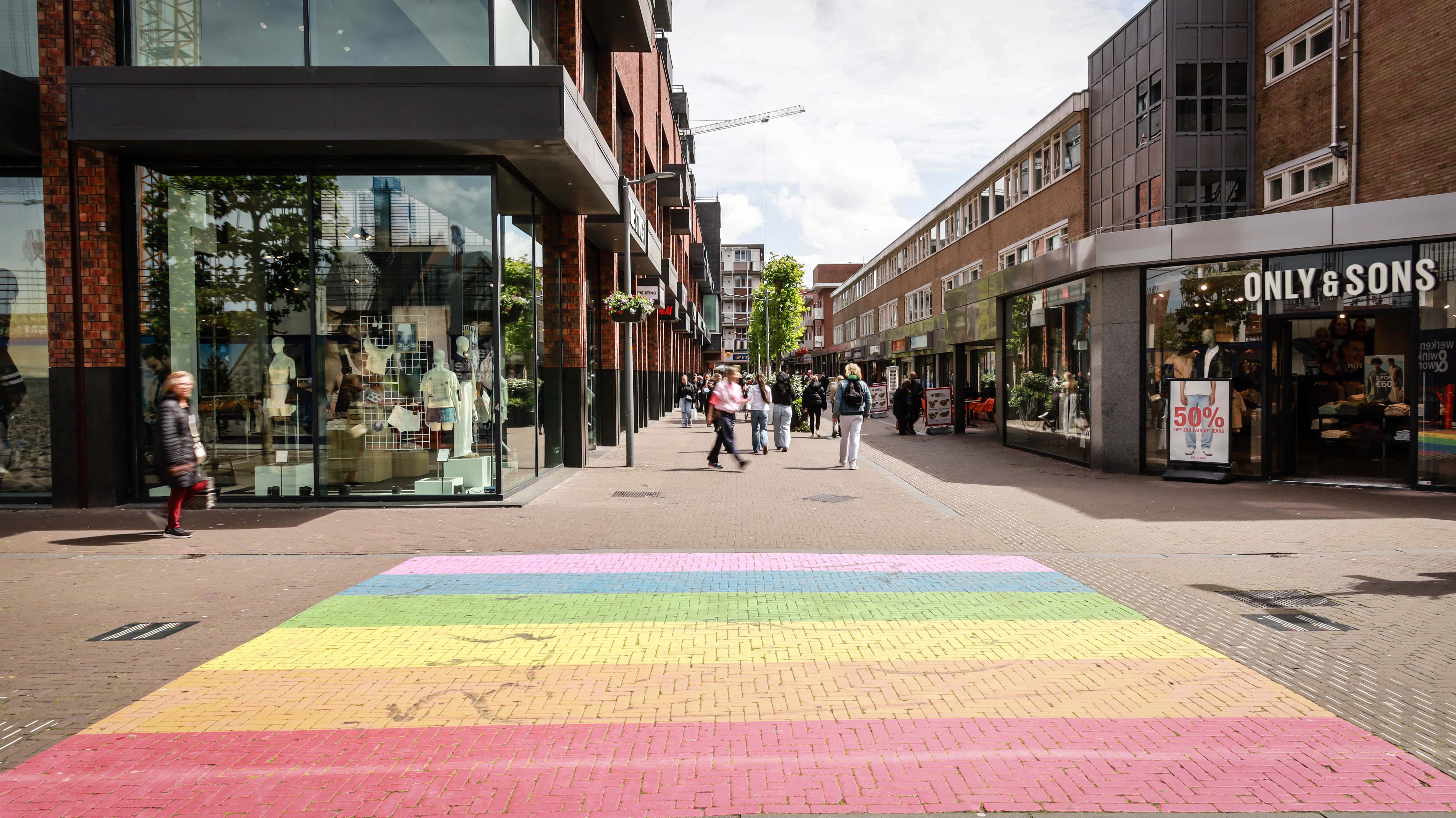 Regenboogzebrapad in winkelstraat met voetgangers