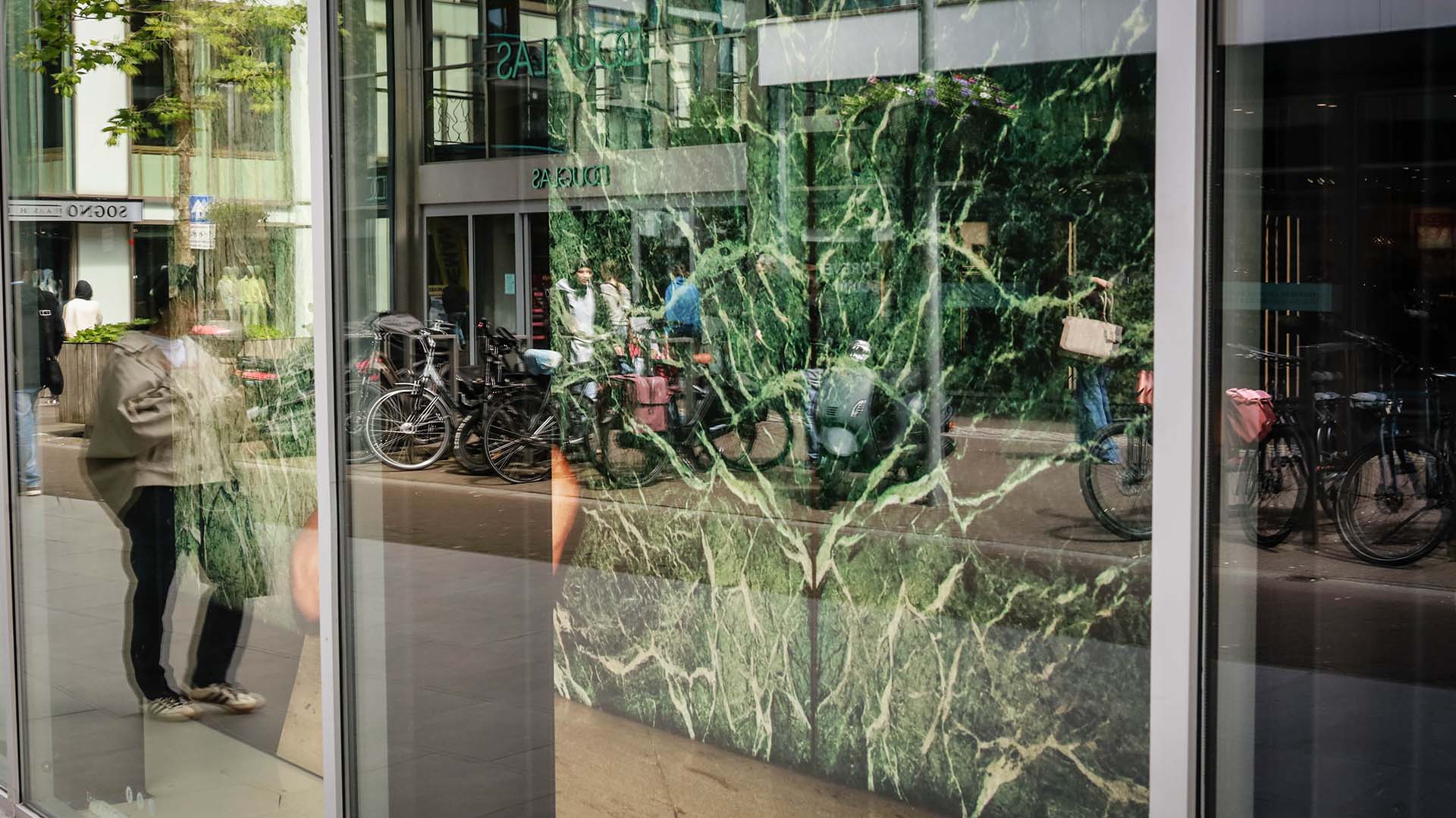 Raam met weerspiegeling van een winkelstraat