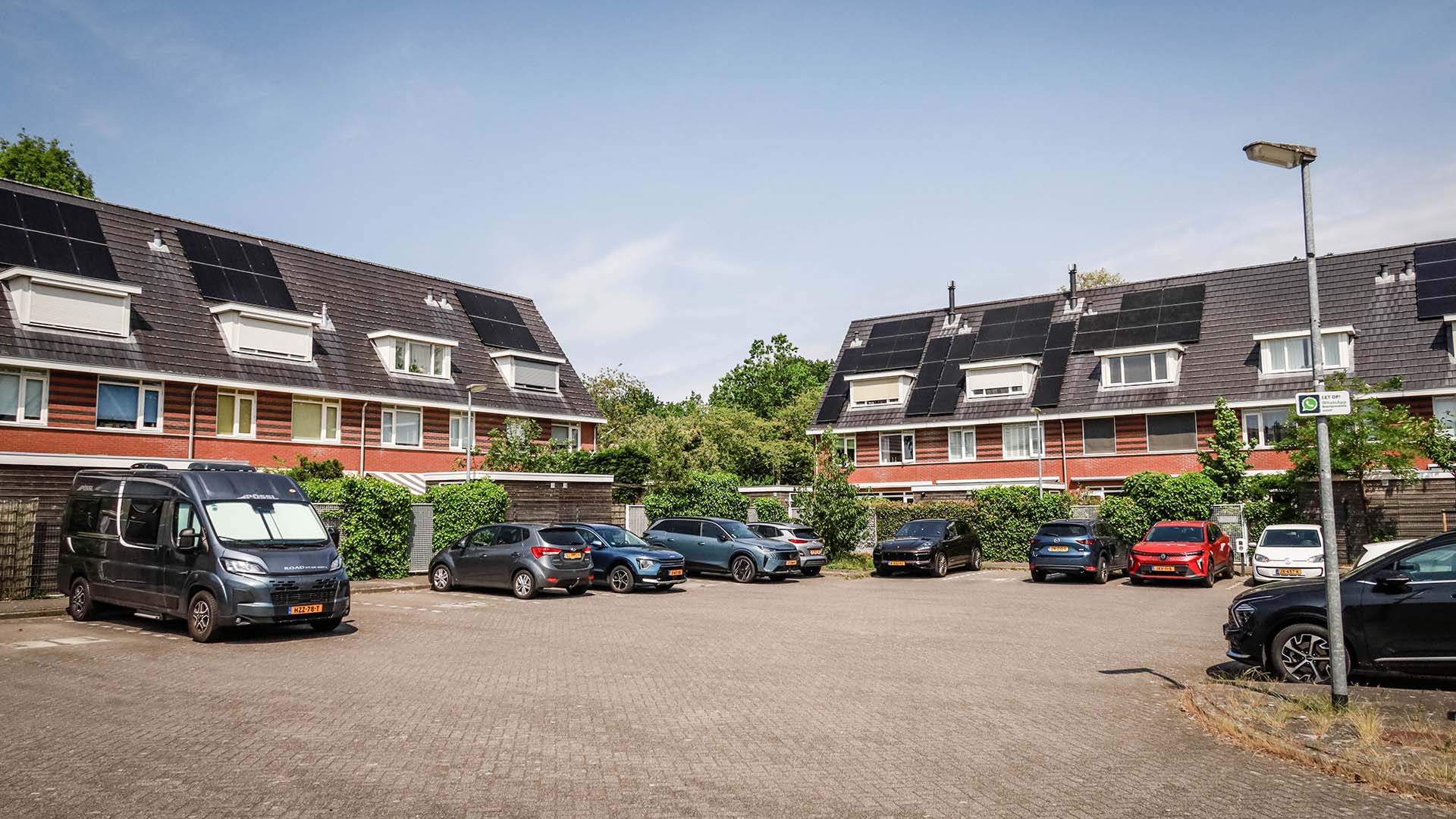 parkeerplein in woonwijk met geparkeerde auto's, rijtjeshuizen op de achtergrond