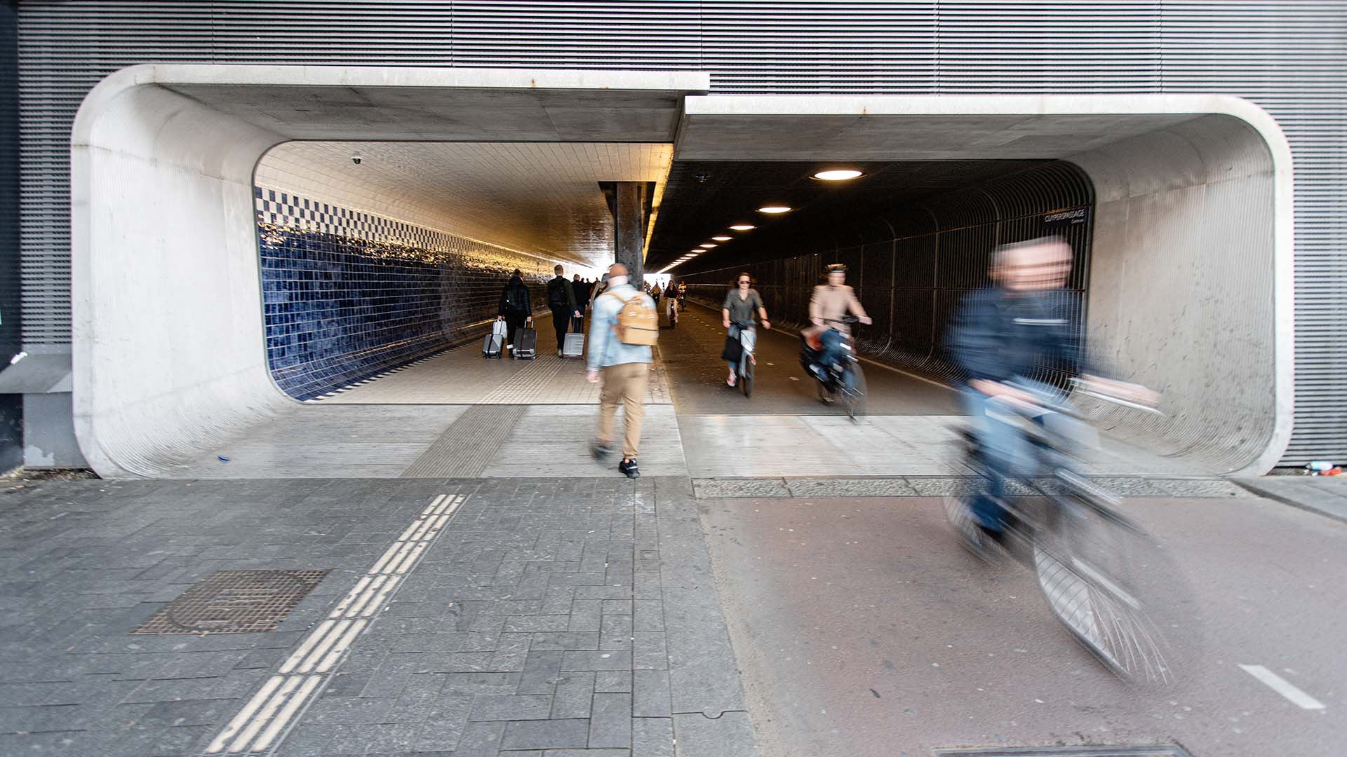 Fietsparkeren en fietstunnel met voetganger en rijdende fietsers.