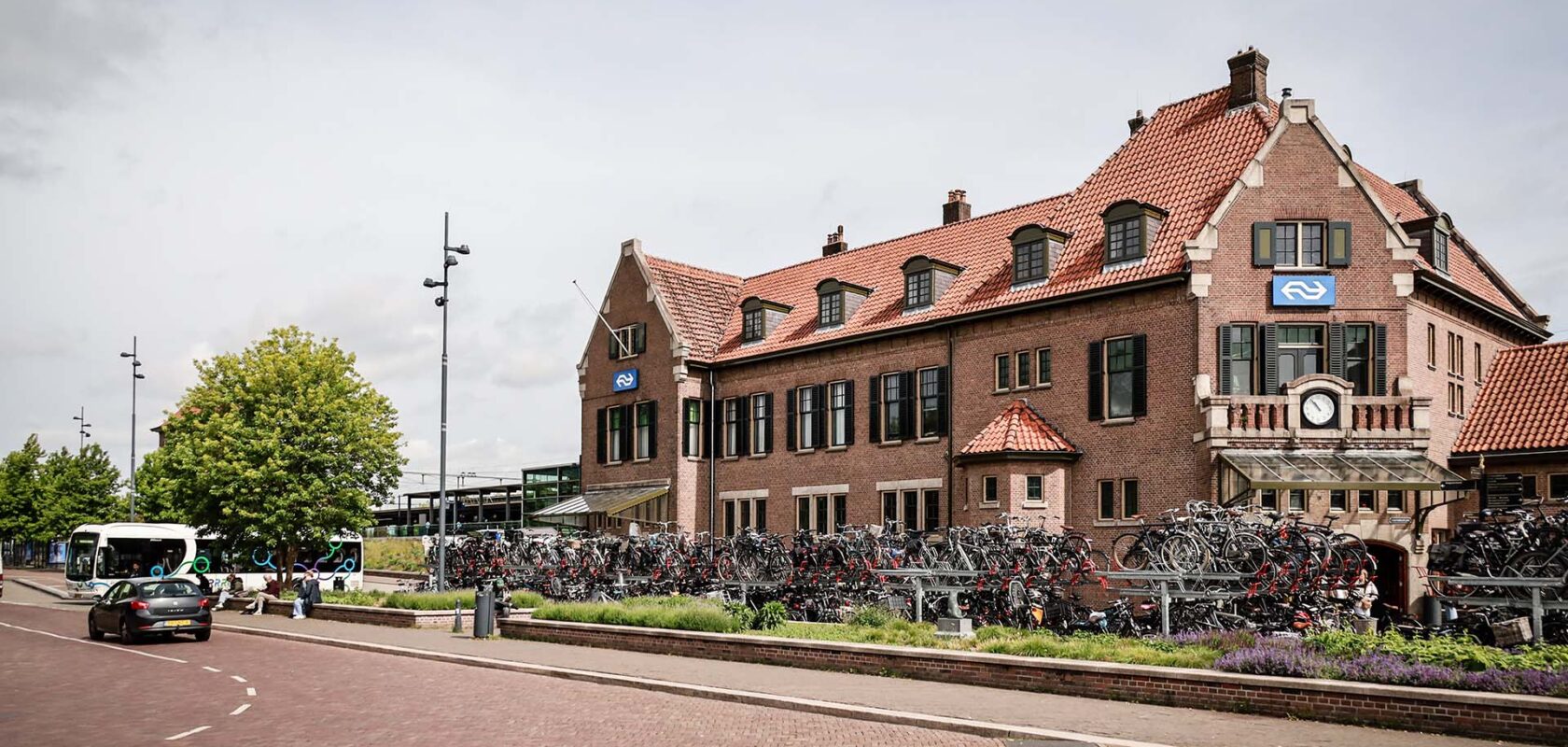 Weg met auto en bus met op achtergrond een bakstenen hotel van drie verdiepingen