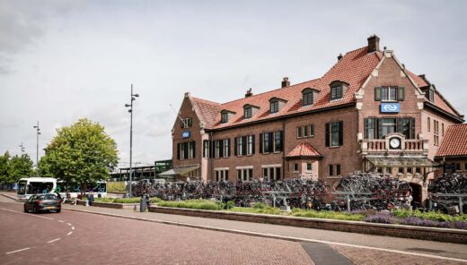 Weg met auto en bus met op achtergrond een bakstenen hotel van drie verdiepingen