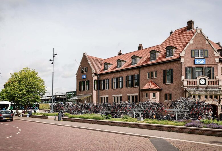 Weg met auto en bus met op achtergrond een bakstenen hotel van drie verdiepingen