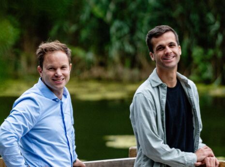 Twee blanke mannen bij een meertje in een groene omgeving
