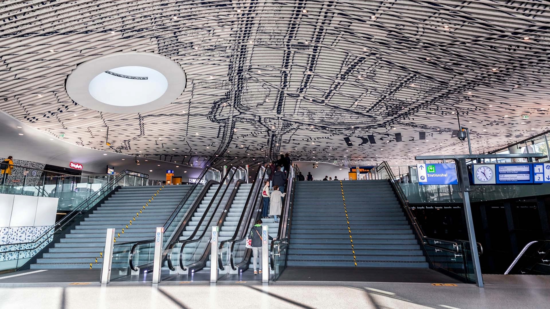 Binnenfoto station met trap, roltrap en zichtbare constructie plafond