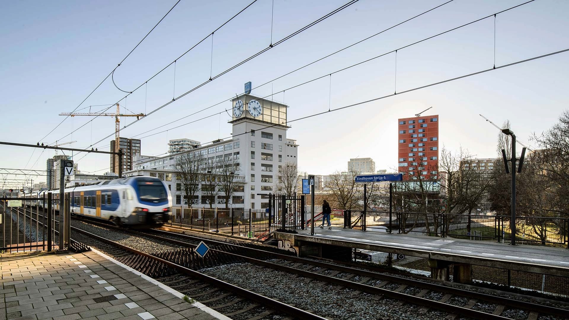 Train op station Eindhoven met klokgebouw Strijp S op achtergrond