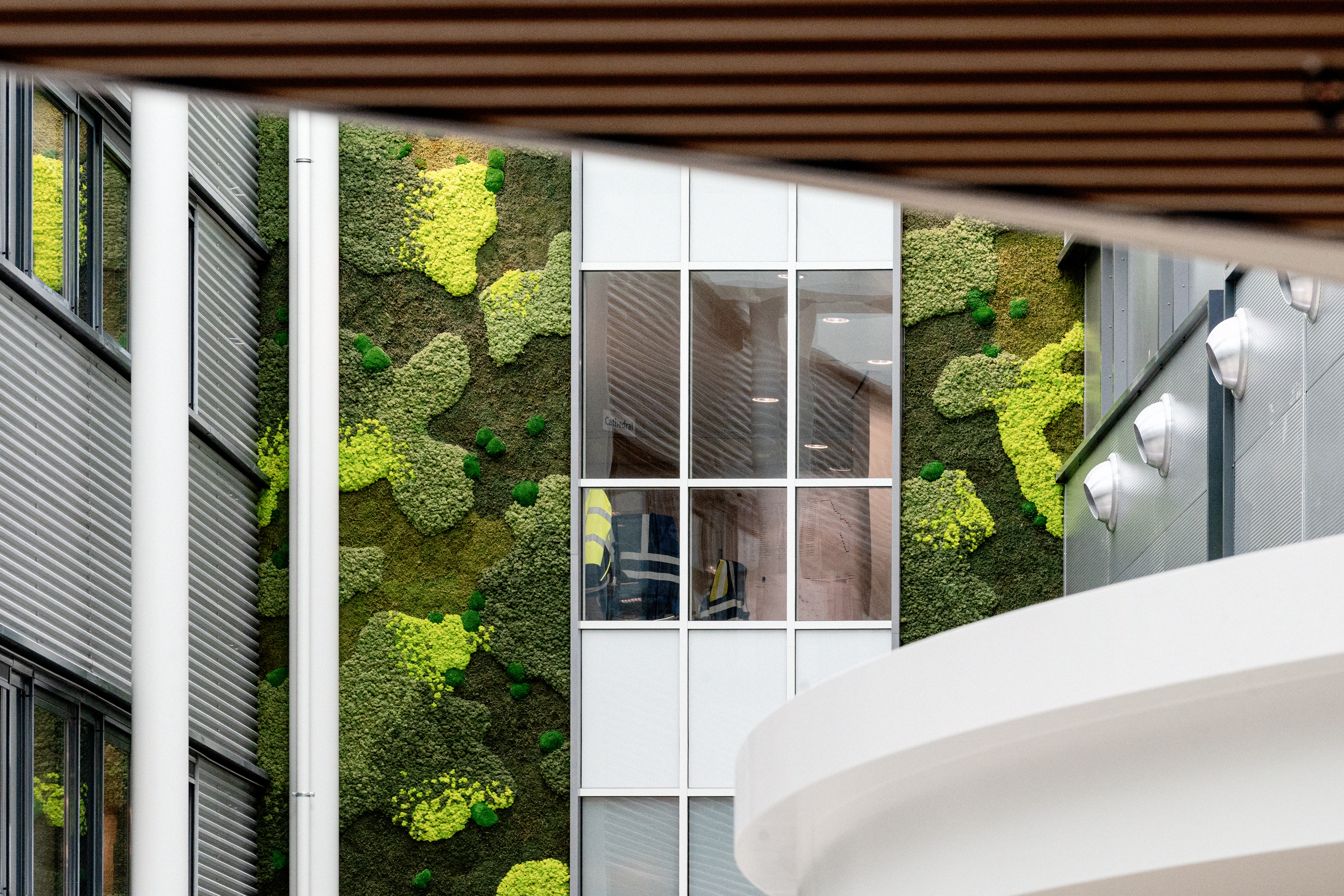 Groene moswand in de centrale hal van de Boston Scientific-campus met veel daglicht en moderne architectuur.