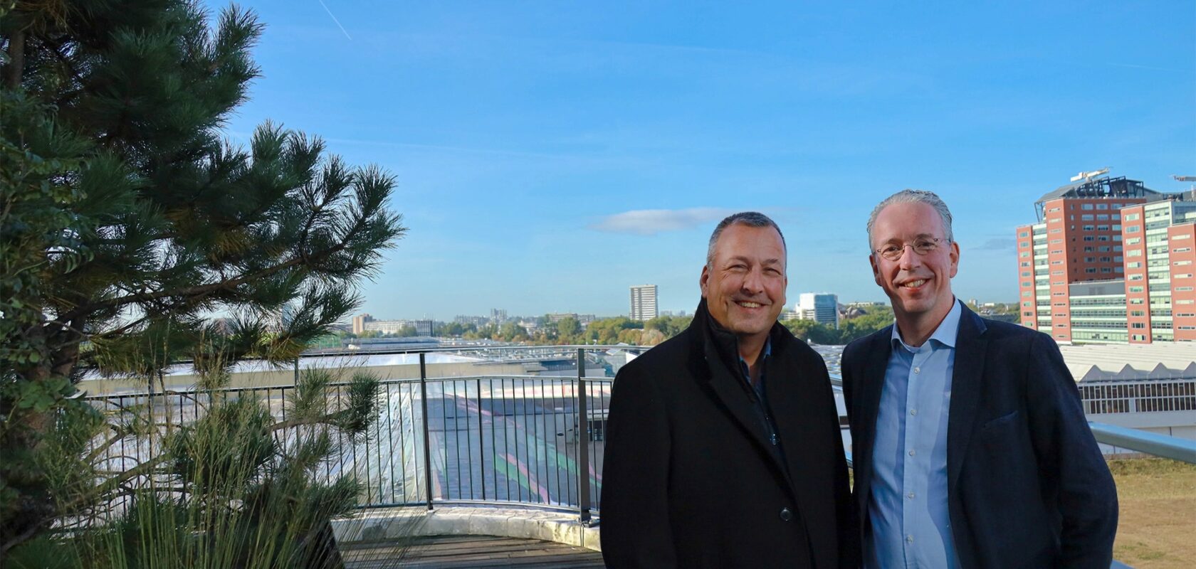 Twee mannen op zonnige dag met hoogbouw op achtergrond