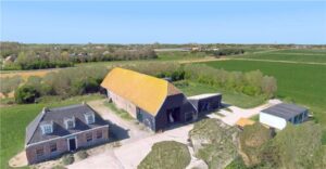 Boerderij met bijgebouwen in plat landelijk gebied.