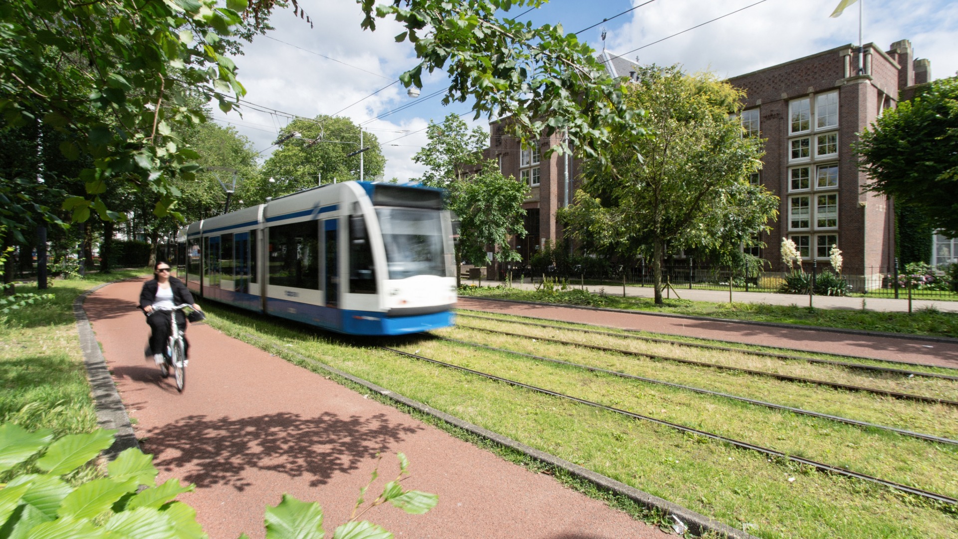 Tram in Amsterdam naast fietspad en groen